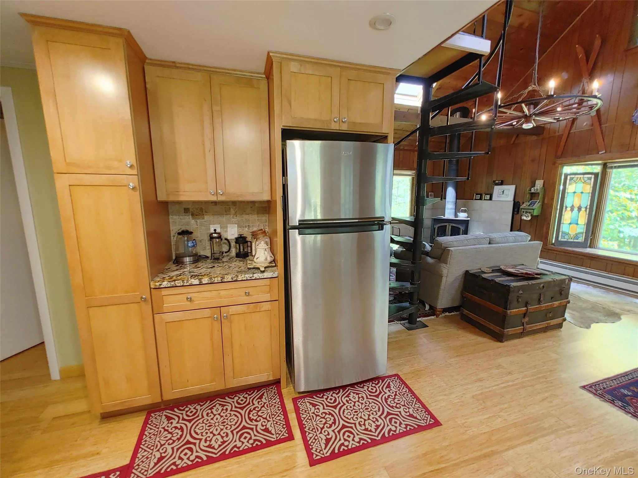 Kitchen with freestanding refrigerator, light bamboo floors, healthy amount of natural light, tasteful stone backsplash, and wood walls Kitchen with freestanding refrigerator, light bamboo floors, healthy amount of natural light, tasteful stone backsplash, and wood walls