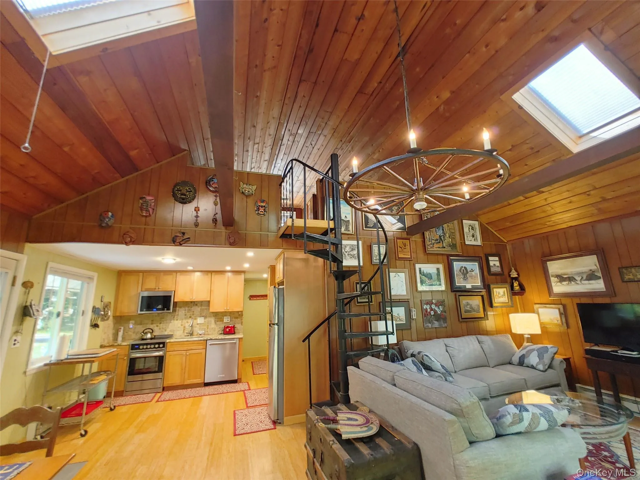 Living room with light wood-type flooring, a chandelier, wood walls, stairs, and a skylight Living room with light wood-type flooring, a chandelier, wood walls, stairs, and a skylight