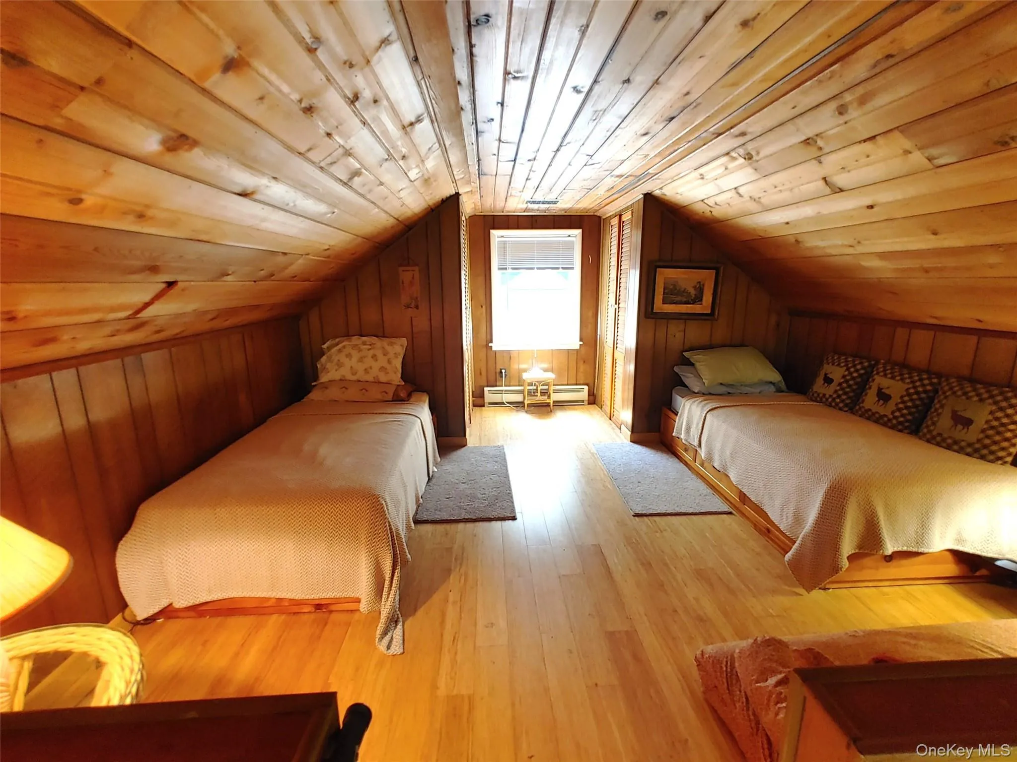 Loft bedroom featuring lofted ceiling, a baseboard radiator, wood walls, bamboo flooring, and wood ceiling Loft bedroom featuring lofted ceiling, a baseboard radiator, wood walls, bamboo flooring, and wood ceiling