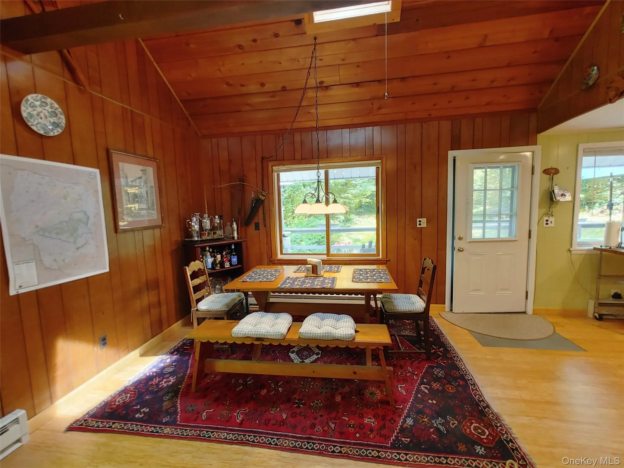 Dining area with vaulted ceiling, wood finished floors, a baseboard heating unit, wood walls, skylights and wooden ceiling Dining area with vaulted ceiling, wood finished floors, a baseboard heating unit, wood walls, skylights and wooden ceiling