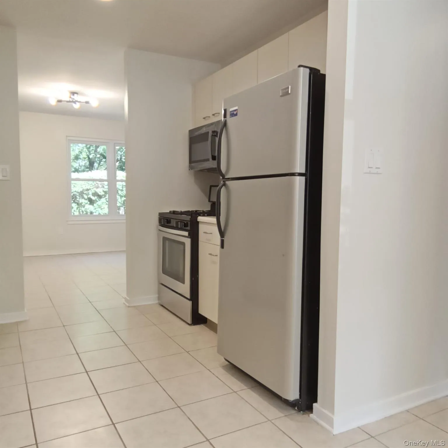 Kitchen with stainless steel appliances, white cabinetry, and light tile patterned floors Kitchen with stainless steel appliances, white cabinetry, and light tile patterned floors