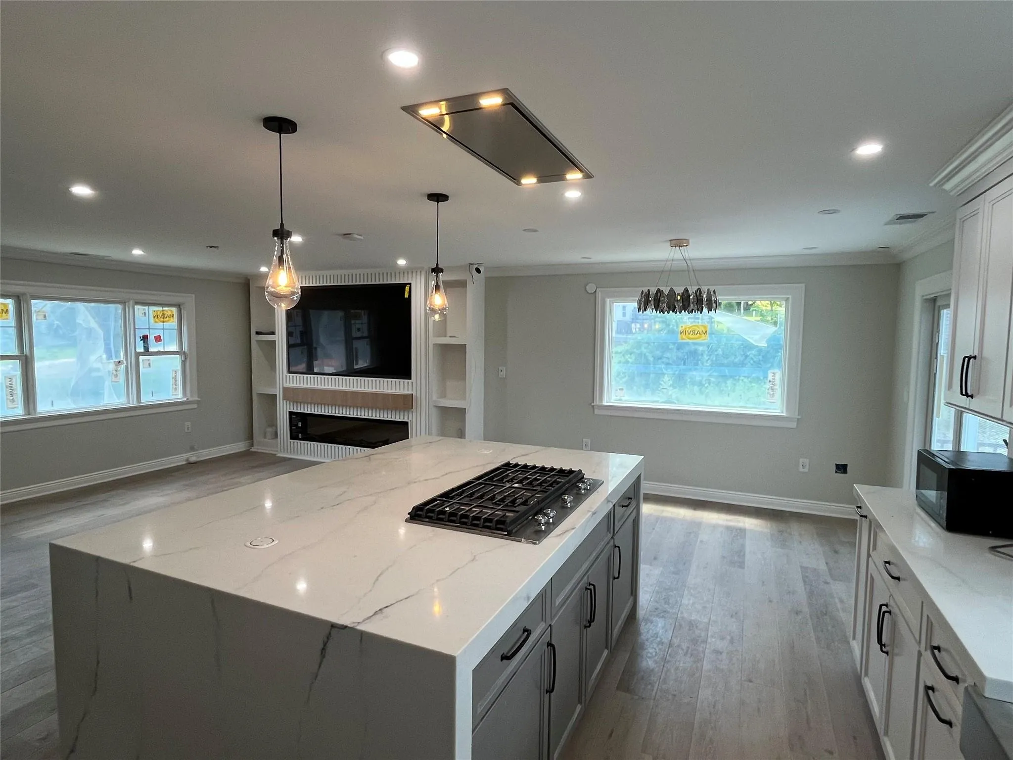 Kitchen with gas stovetop, crown molding, light wood-style floors, black microwave, and light stone counters Kitchen with gas stovetop, crown molding, light wood-style floors, black microwave, and light stone counters