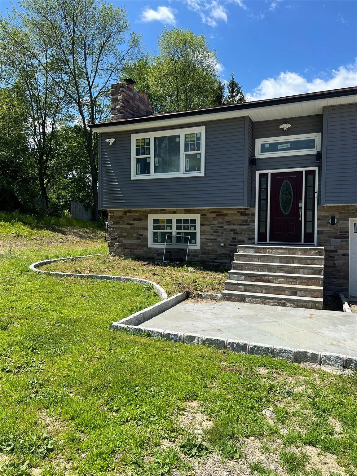 Tri-level home featuring a chimney, entry steps, a front lawn, and stone siding Tri-level home featuring a chimney, entry steps, a front lawn, and stone siding