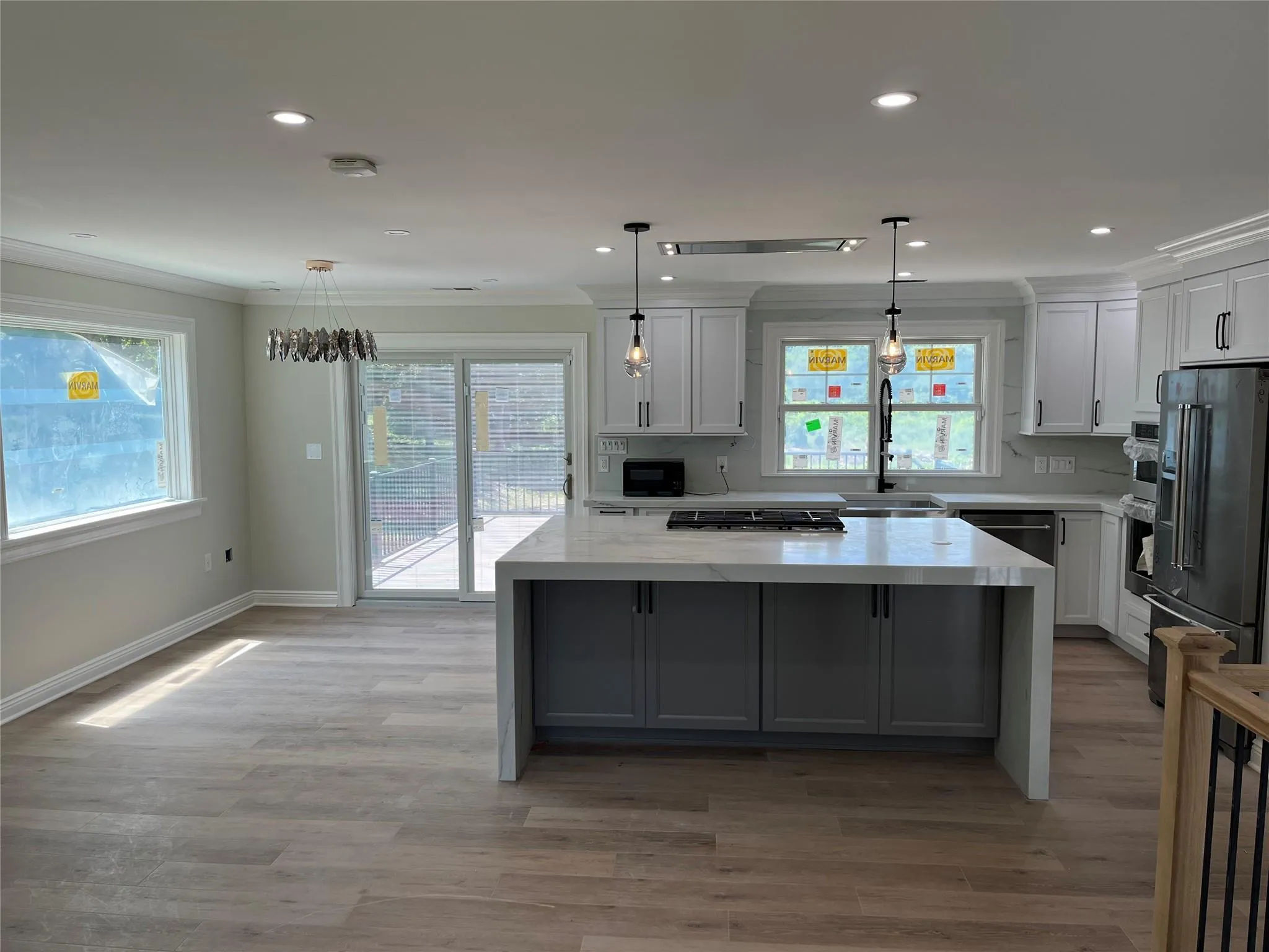 Kitchen with crown molding, high end refrigerator, a kitchen island, light wood-style flooring, and white cabinetry Kitchen with crown molding, high end refrigerator, a kitchen island, light wood-style flooring, and white cabinetry