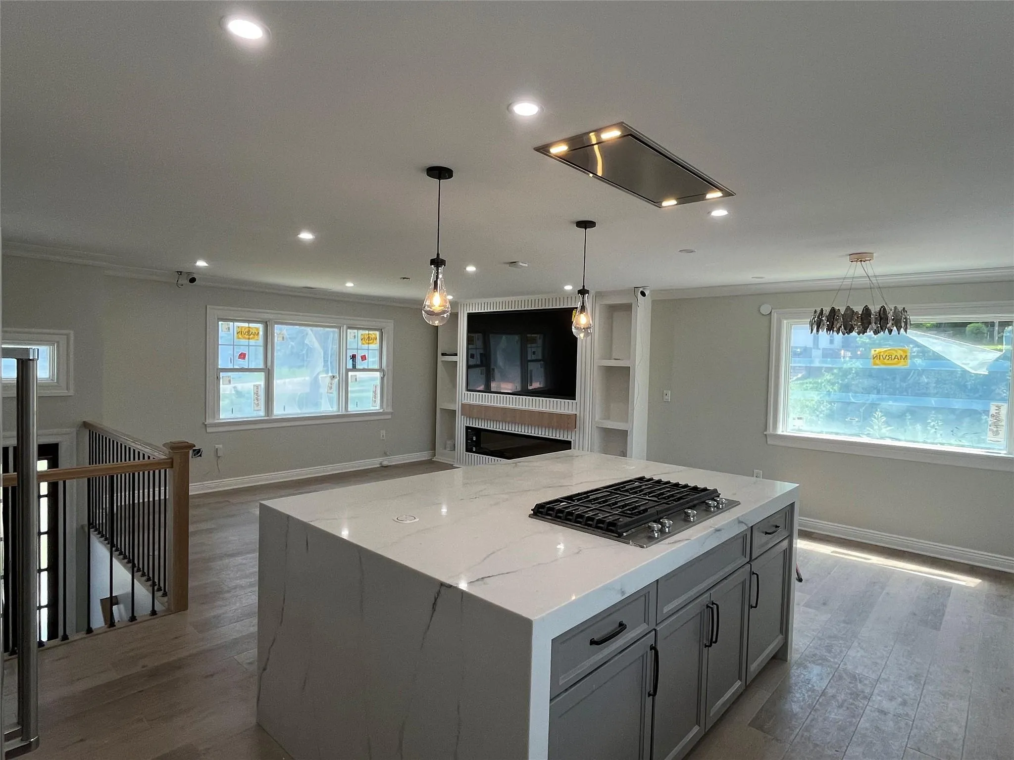 Kitchen with stainless steel gas stovetop, open floor plan, light wood-type flooring, ornamental molding, and light stone countertops Kitchen with stainless steel gas stovetop, open floor plan, light wood-type flooring, ornamental molding, and light stone countertops
