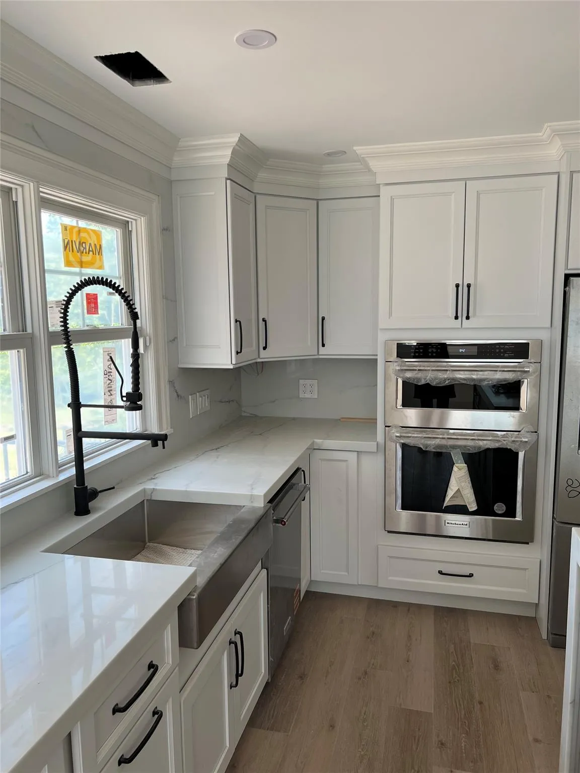 Kitchen with appliances with stainless steel finishes, plenty of natural light, white cabinets, and light wood finished floors Kitchen with appliances with stainless steel finishes, plenty of natural light, white cabinets, and light wood finished floors