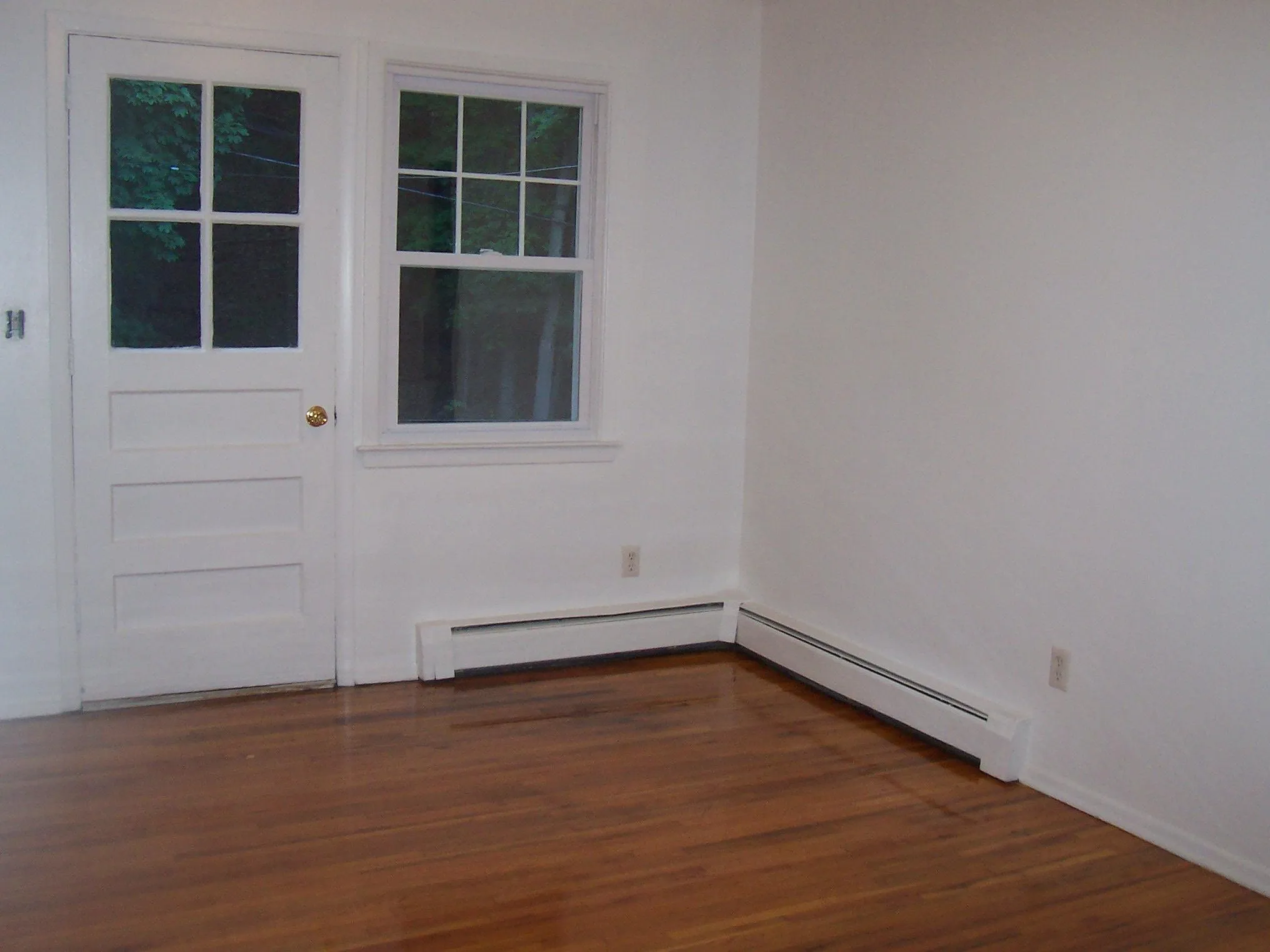 Unfurnished room featuring wood finished floors and baseboard heating Unfurnished room featuring wood finished floors and baseboard heating