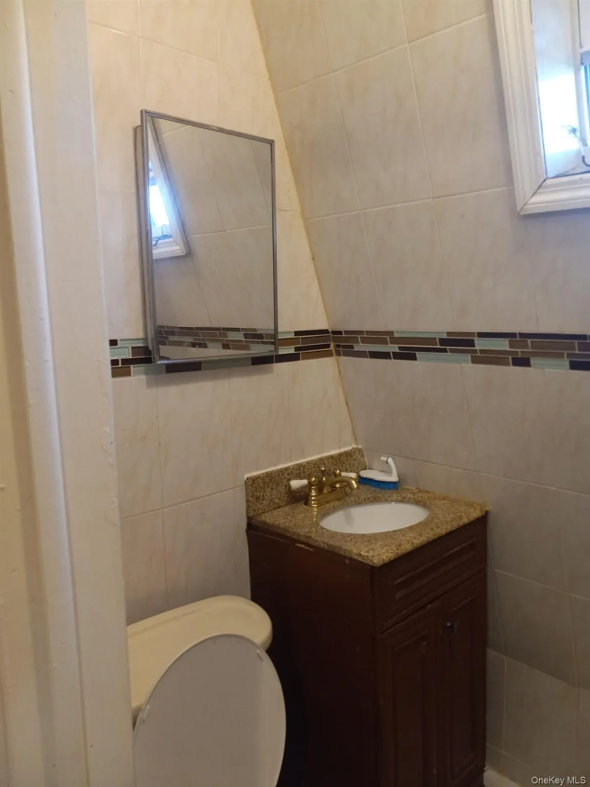 Bathroom with tile walls, vanity, and healthy amount of natural light Bathroom with tile walls, vanity, and healthy amount of natural light