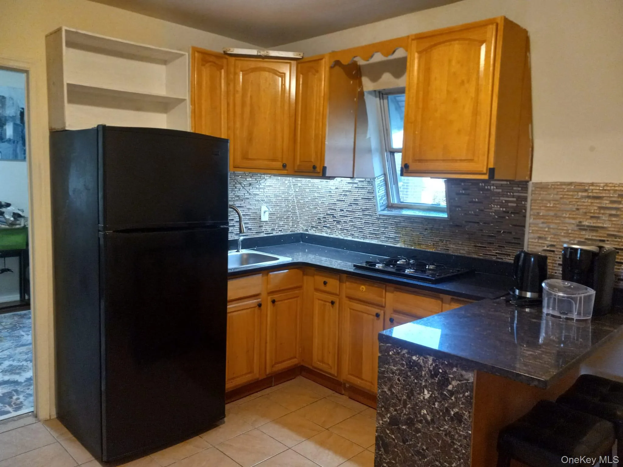 Kitchen featuring black appliances, a peninsula, light tile patterned flooring, backsplash, and a kitchen bar Kitchen featuring black appliances, a peninsula, light tile patterned flooring, backsplash, and a kitchen bar