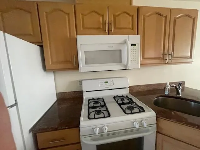 Kitchen with white appliances and dark stone countertops Kitchen with white appliances and dark stone countertops