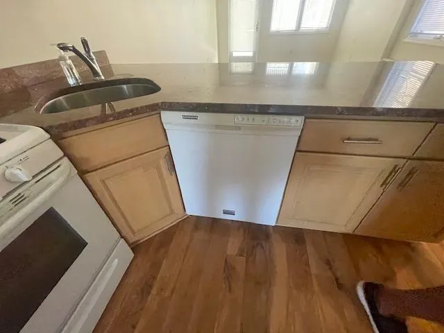 Kitchen with white appliances, dark wood-style flooring, and dark stone countertops Kitchen with white appliances, dark wood-style flooring, and dark stone countertops