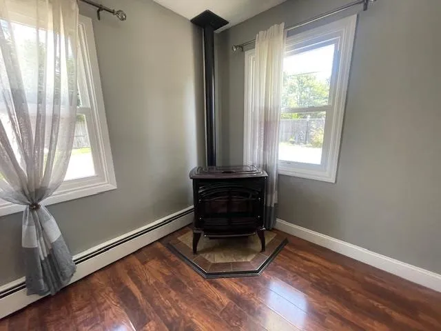 Detailed view of a wood stove, a baseboard radiator, and wood finished floors Detailed view of a wood stove, a baseboard radiator, and wood finished floors