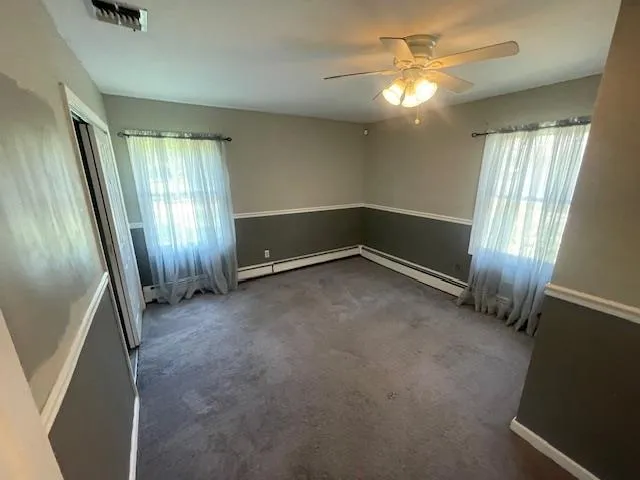 Carpeted Bedroom with plenty of natural light, baseboard heating, and a ceiling fan Carpeted Bedroom with plenty of natural light, baseboard heating, and a ceiling fan