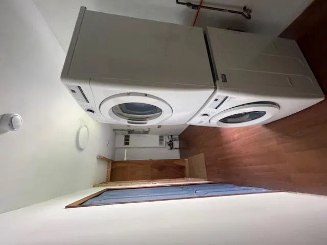 Washroom featuring estacked washer and dryer and wood finished floors Washroom featuring estacked washer and dryer and wood finished floors