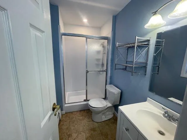 Full bathroom featuring a shower stall, vanity, and tile patterned flooring Full bathroom featuring a shower stall, vanity, and tile patterned flooring