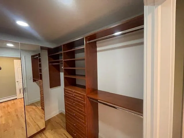 Walk in closet featuring light wood finished floors Walk in closet featuring light wood finished floors