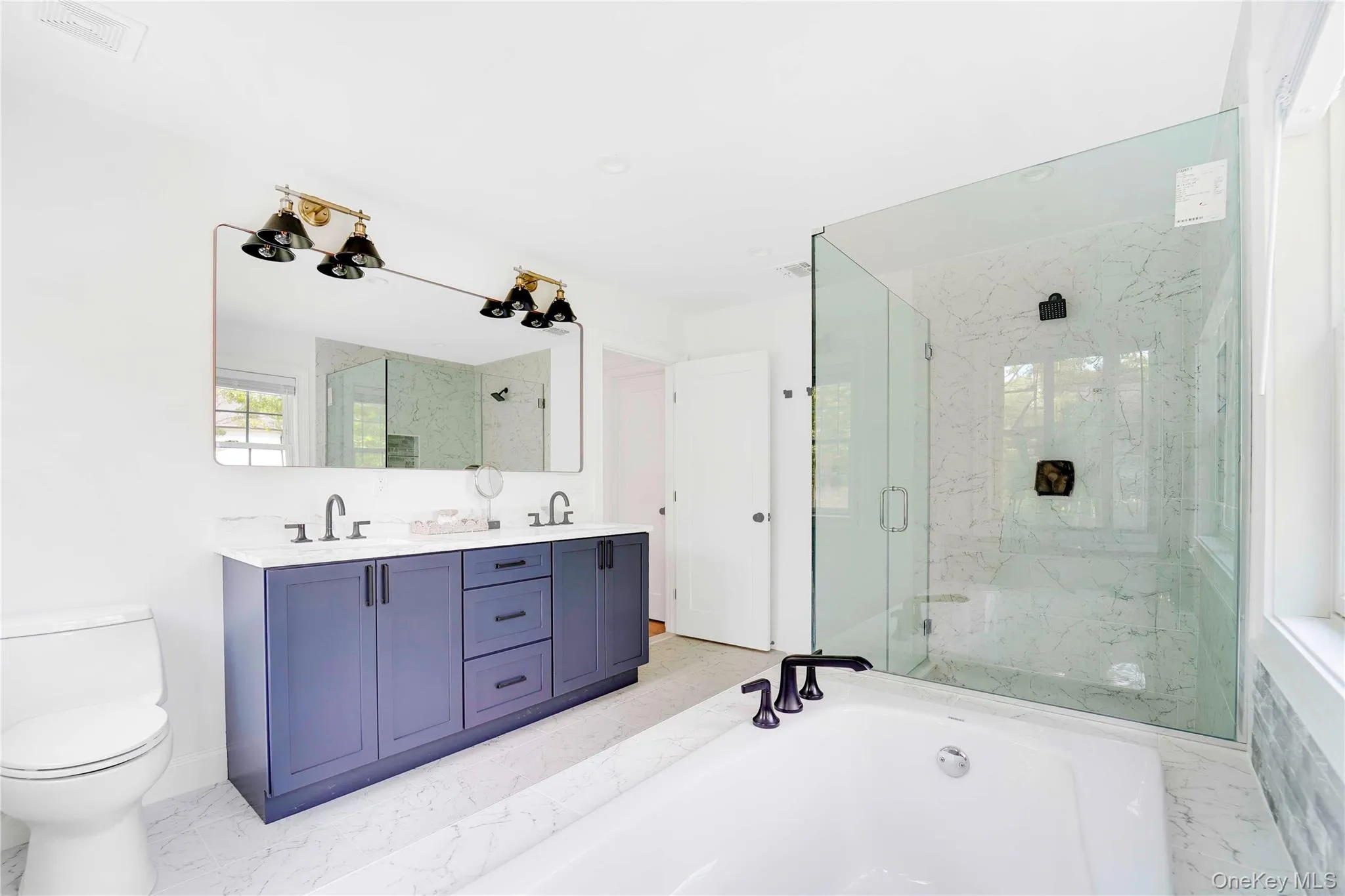 Primary Bathroom featuring a bath, a marble finish shower, and double vanity Primary Bathroom featuring a bath, a marble finish shower, and double vanity
