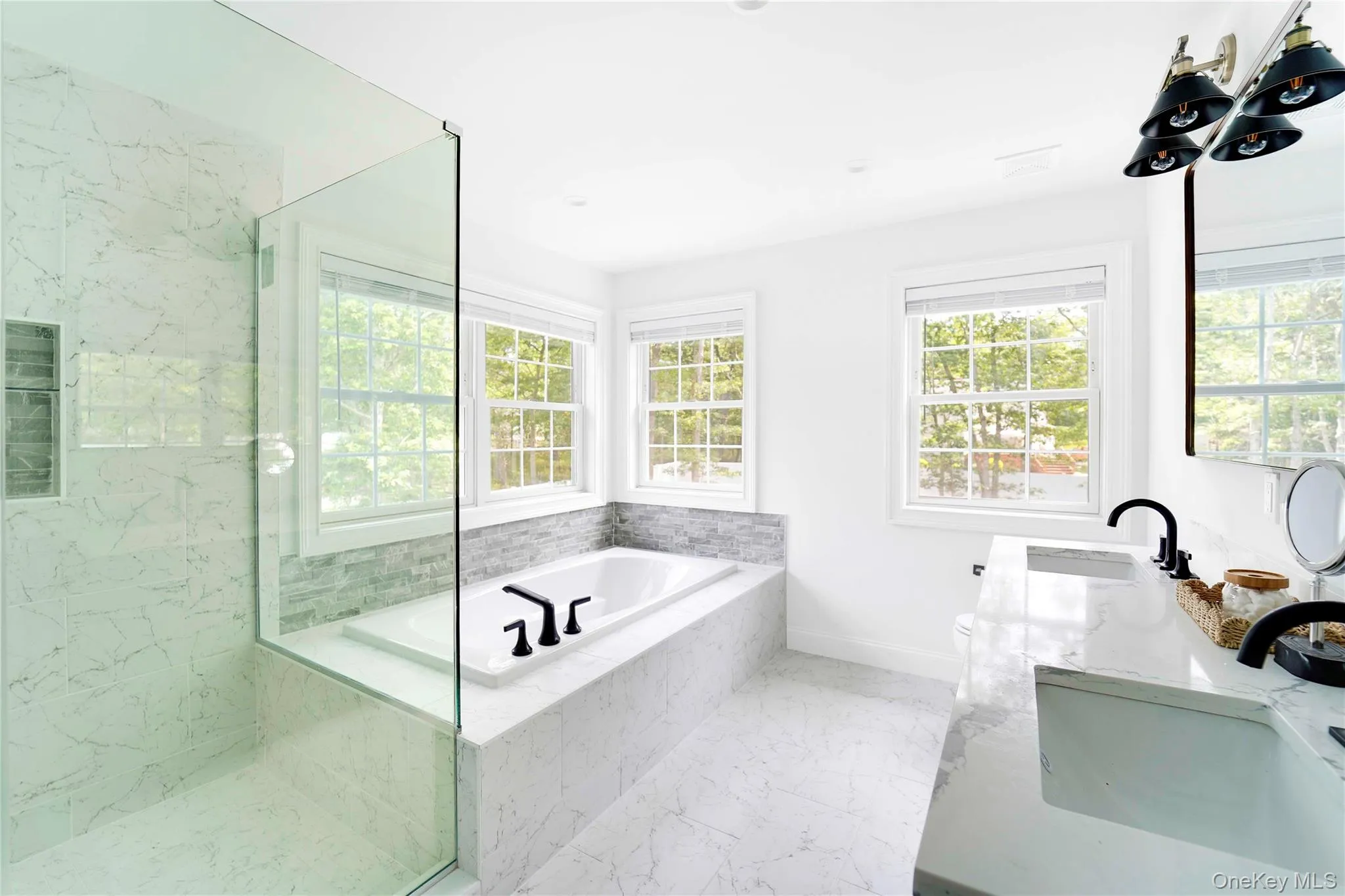 Primary bathroom featuring a garden tub, marble finish floors, double vanity, and a marble finish shower Primary bathroom featuring a garden tub, marble finish floors, double vanity, and a marble finish shower