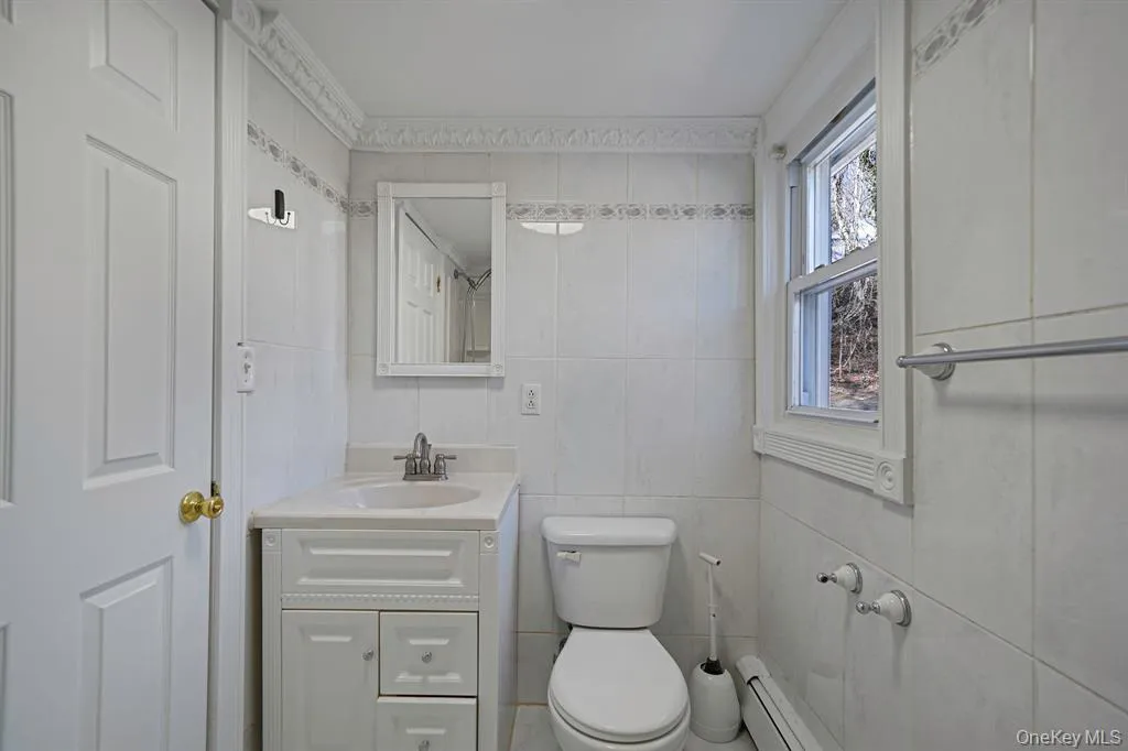 Bathroom with vanity, tile walls, and a baseboard radiator Bathroom with vanity, tile walls, and a baseboard radiator