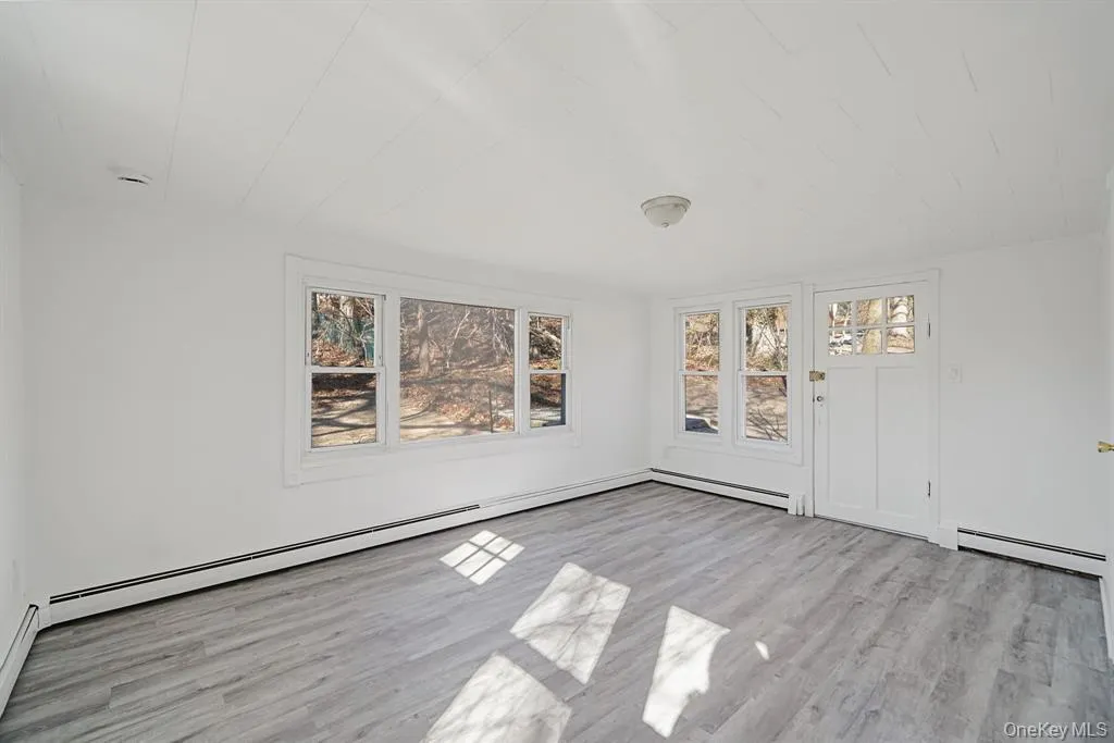 Unfurnished room featuring wood finished floors and a baseboard radiator Unfurnished room featuring wood finished floors and a baseboard radiator