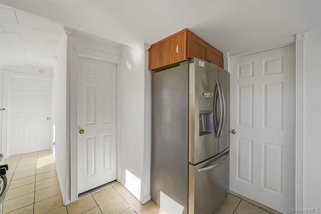 Kitchen with stainless steel fridge, brown cabinets, and light tile patterned floors Kitchen with stainless steel fridge, brown cabinets, and light tile patterned floors