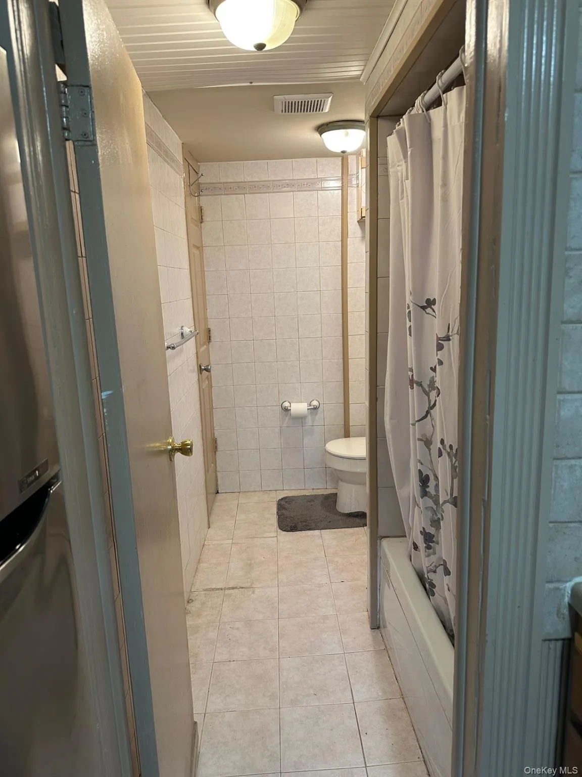 Full bathroom featuring tile patterned flooring, tile walls, and shower / bath combo Full bathroom featuring tile patterned flooring, tile walls, and shower / bath combo