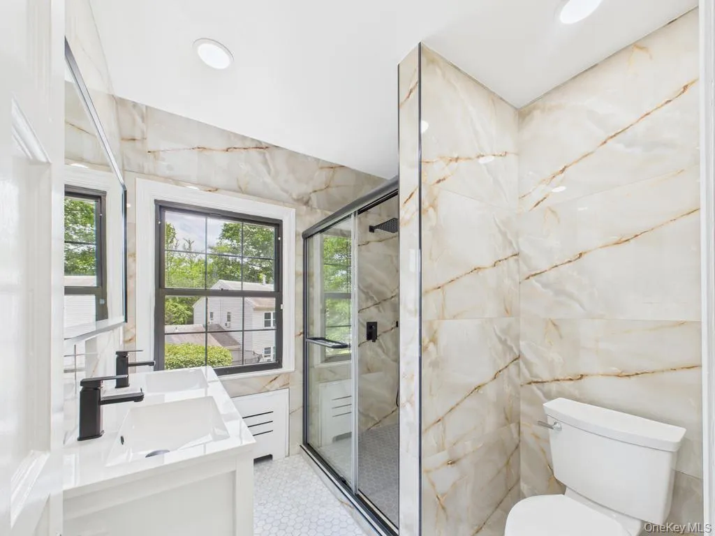Bathroom featuring tile walls, vanity, a marble finish shower, and recessed lighting Bathroom featuring tile walls, vanity, a marble finish shower, and recessed lighting