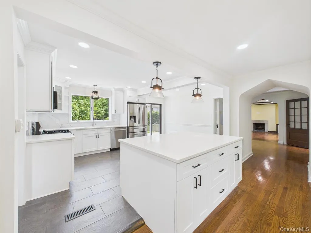 Kitchen with appliances with stainless steel finishes, crown molding, white cabinetry, hanging light fixtures, and recessed lighting Kitchen with appliances with stainless steel finishes, crown molding, white cabinetry, hanging light fixtures, and recessed lighting