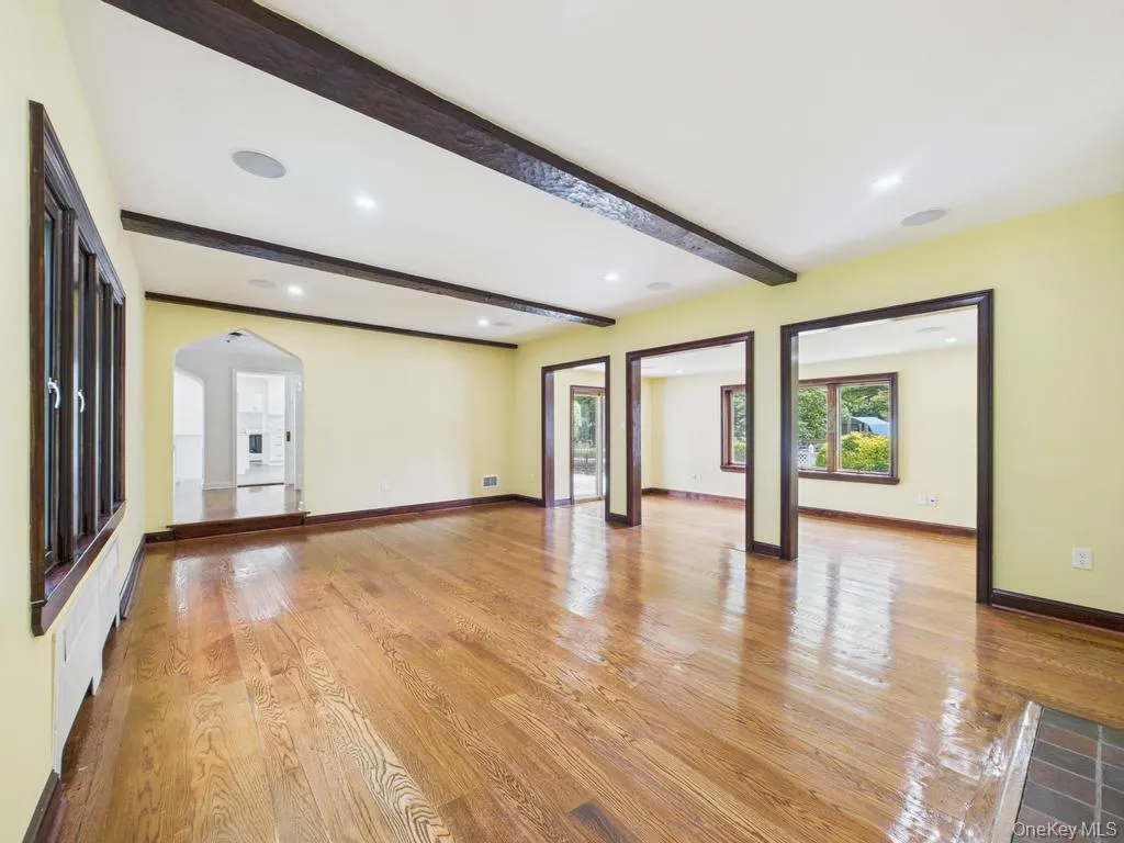 Unfurnished living room featuring beam ceiling, arched walkways, light wood-style flooring, and recessed lighting Unfurnished living room featuring beam ceiling, arched walkways, light wood-style flooring, and recessed lighting