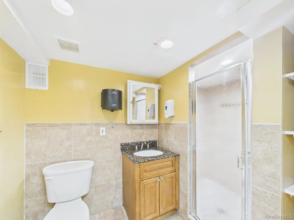 Full bathroom with tile walls, vanity, a wainscoted wall, and a stall shower Full bathroom with tile walls, vanity, a wainscoted wall, and a stall shower