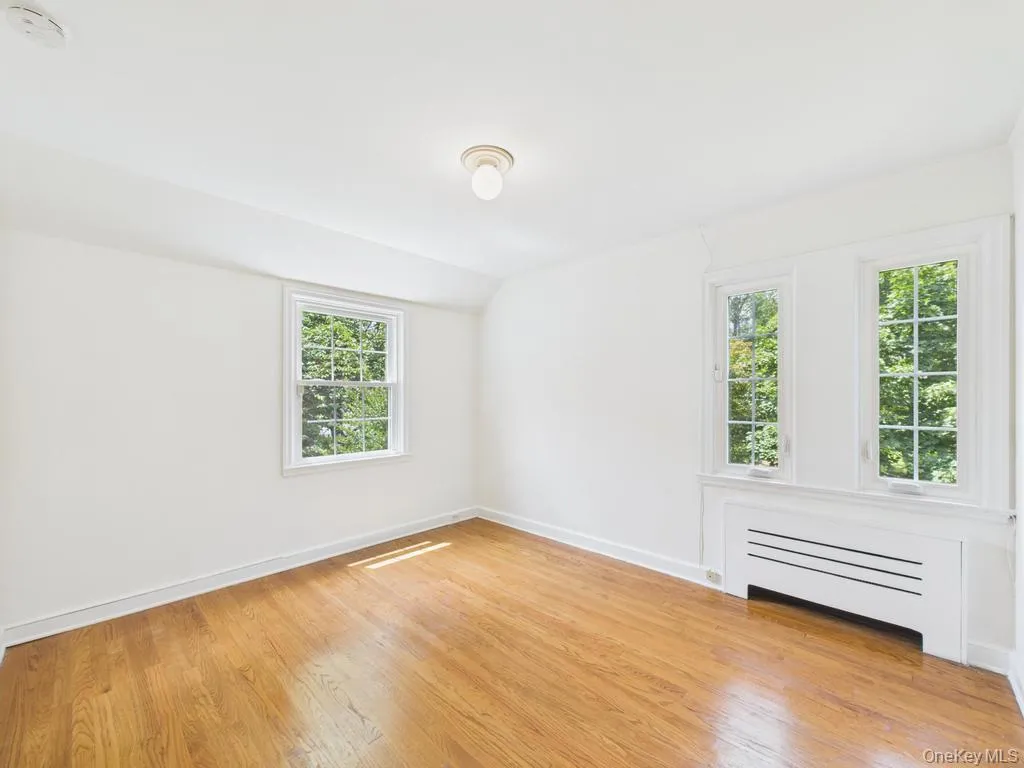 Unfurnished room featuring healthy amount of natural light, light wood-type flooring, a smoke detector, and vaulted ceiling Unfurnished room featuring healthy amount of natural light, light wood-type flooring, a smoke detector, and vaulted ceiling