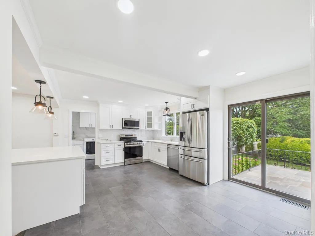 Kitchen with appliances with stainless steel finishes, healthy amount of natural light, washer / clothes dryer, light countertops, and ornamental molding Kitchen with appliances with stainless steel finishes, healthy amount of natural light, washer / clothes dryer, light countertops, and ornamental molding