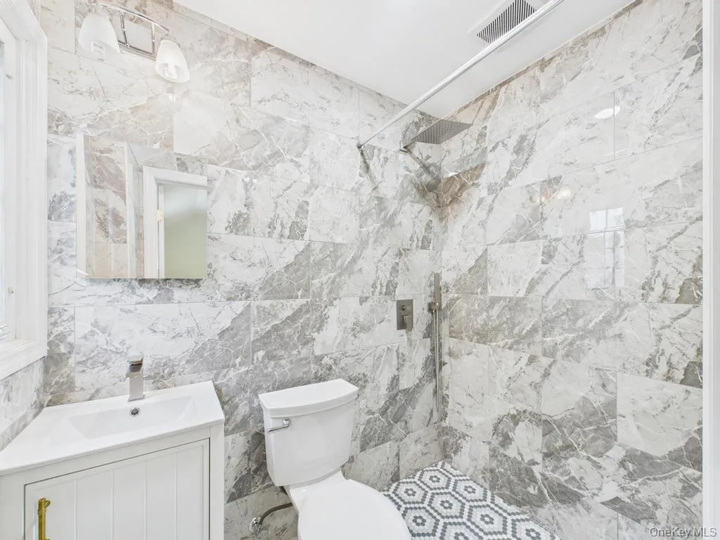 Full bathroom with a tile shower, vanity, and tile walls Full bathroom with a tile shower, vanity, and tile walls