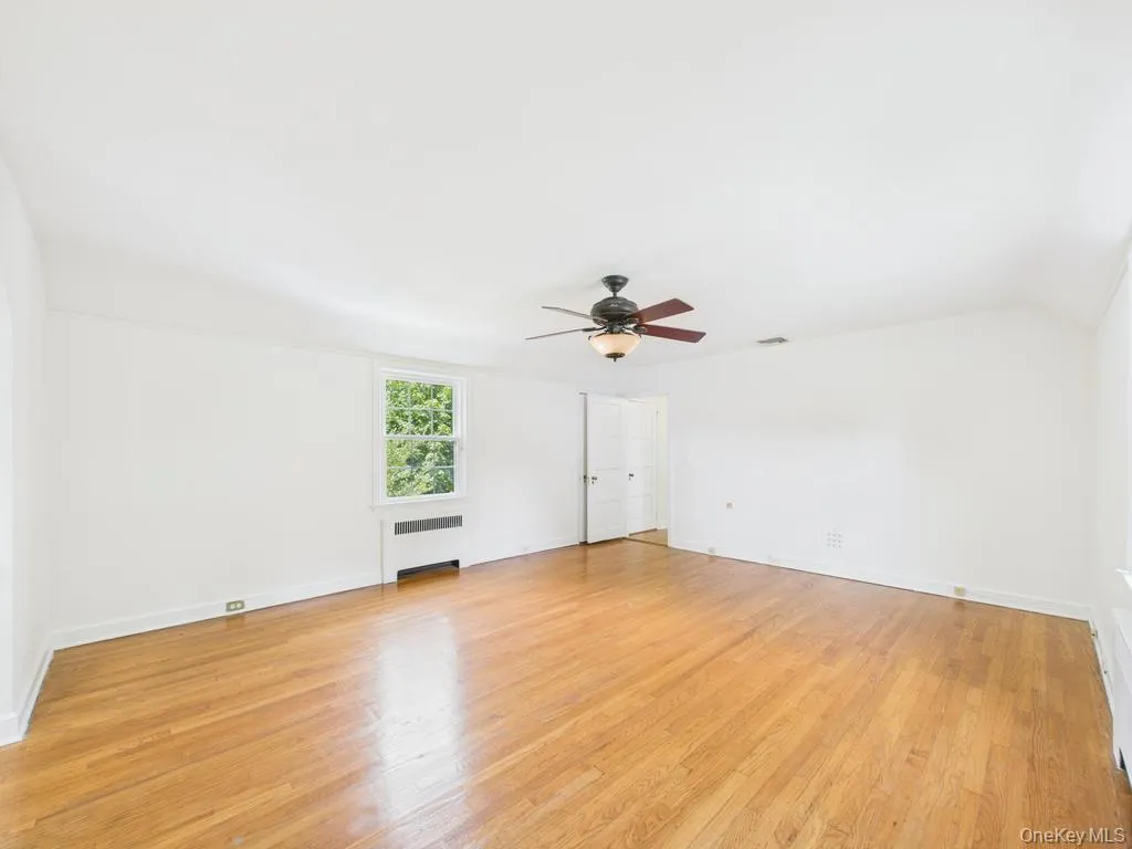 Empty room with radiator, a ceiling fan, and light wood-style floors Empty room with radiator, a ceiling fan, and light wood-style floors