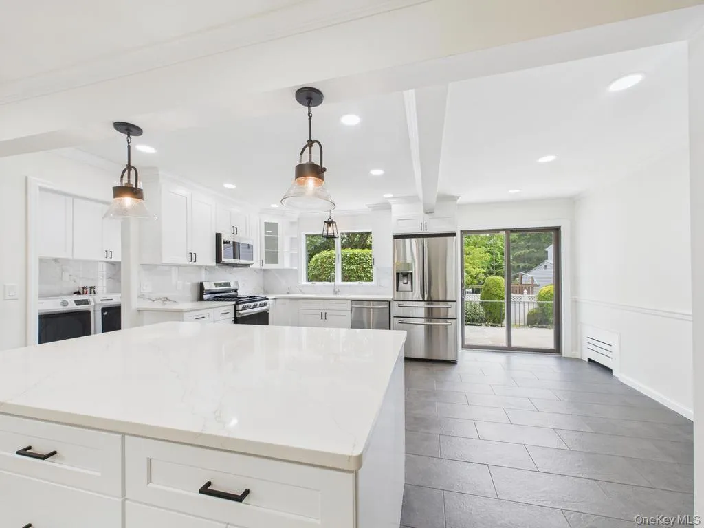 Kitchen with appliances with stainless steel finishes, washing machine and dryer, tasteful backsplash, healthy amount of natural light, and recessed lighting Kitchen with appliances with stainless steel finishes, washing machine and dryer, tasteful backsplash, healthy amount of natural light, and recessed lighting