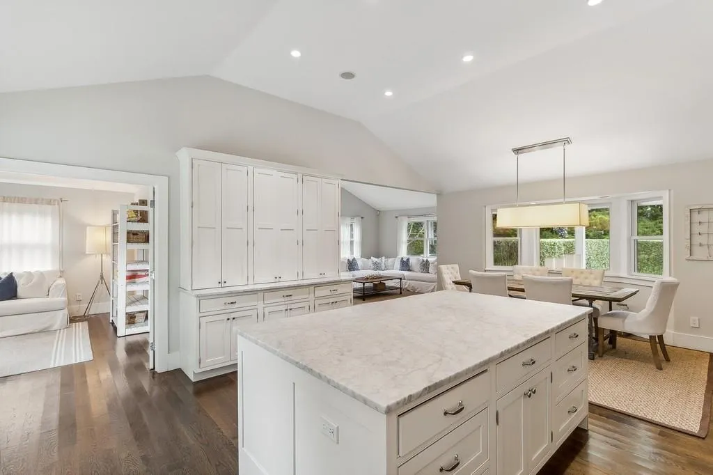 Kitchen featuring lofted ceiling, open floor plan, dark wood-style floors, white cabinets, and light stone counters Kitchen featuring lofted ceiling, open floor plan, dark wood-style floors, white cabinets, and light stone counters