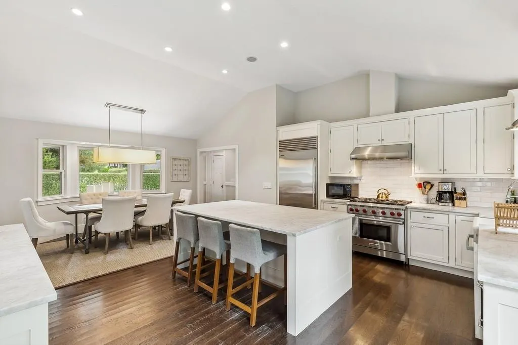 Kitchen featuring high end appliances, under cabinet range hood, lofted ceiling, a center island, and dark wood-type flooring Kitchen featuring high end appliances, under cabinet range hood, lofted ceiling, a center island, and dark wood-type flooring