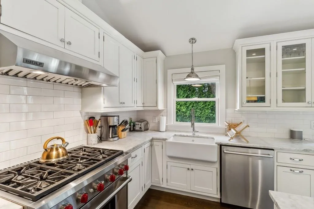 Kitchen featuring stainless steel appliances, under cabinet range hood, white cabinets, and tasteful backsplash Kitchen featuring stainless steel appliances, under cabinet range hood, white cabinets, and tasteful backsplash