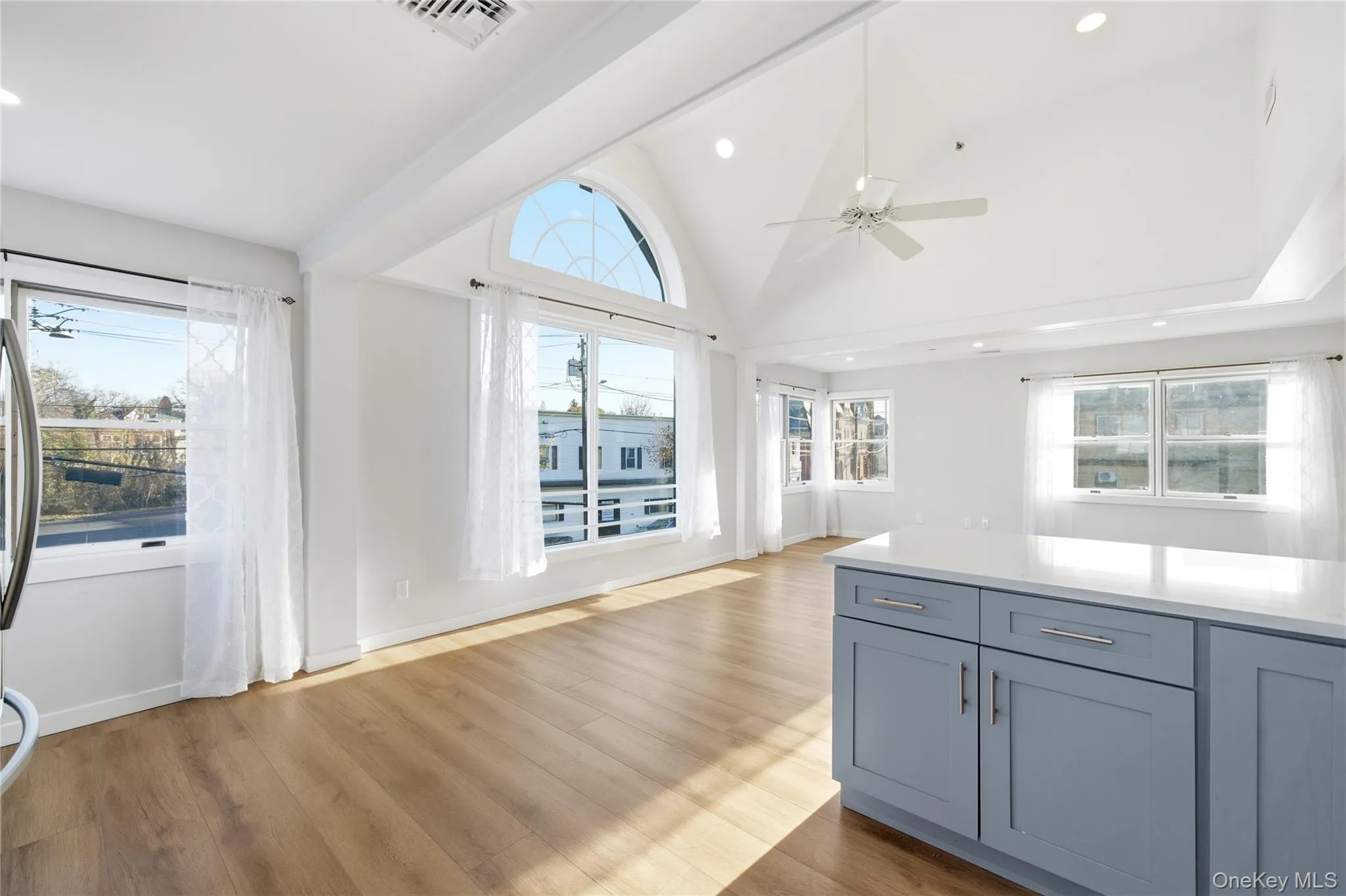 Kitchen featuring high vaulted ceiling, healthy amount of natural light, light wood-style floors, open floor plan, and light stone counters Kitchen featuring high vaulted ceiling, healthy amount of natural light, light wood-style floors, open floor plan, and light stone counters
