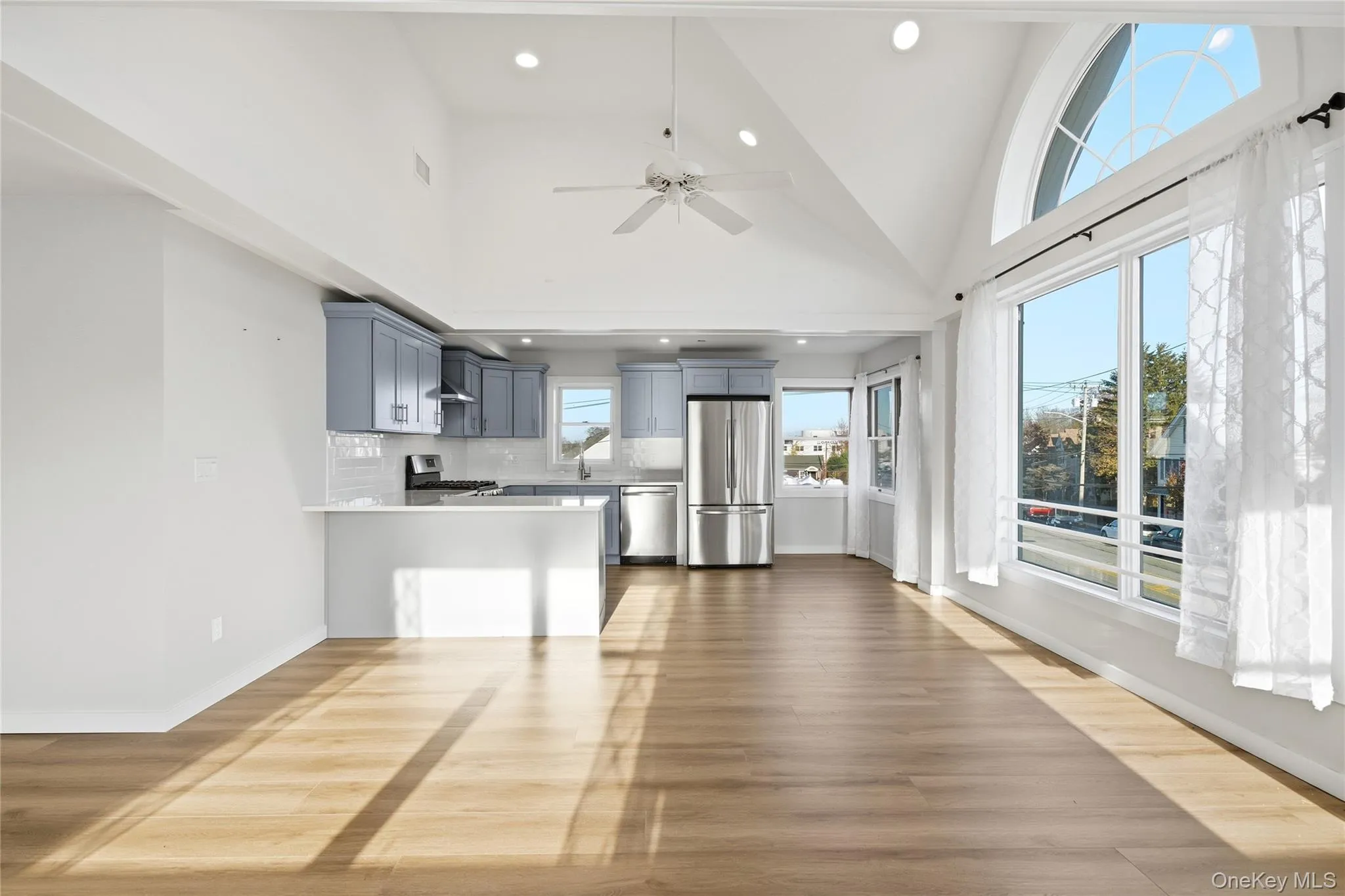 Dining area with high vaulted ceiling, light wood-style flooring, ceiling fan, and open floor plan Dining area with high vaulted ceiling, light wood-style flooring, ceiling fan, and open floor plan