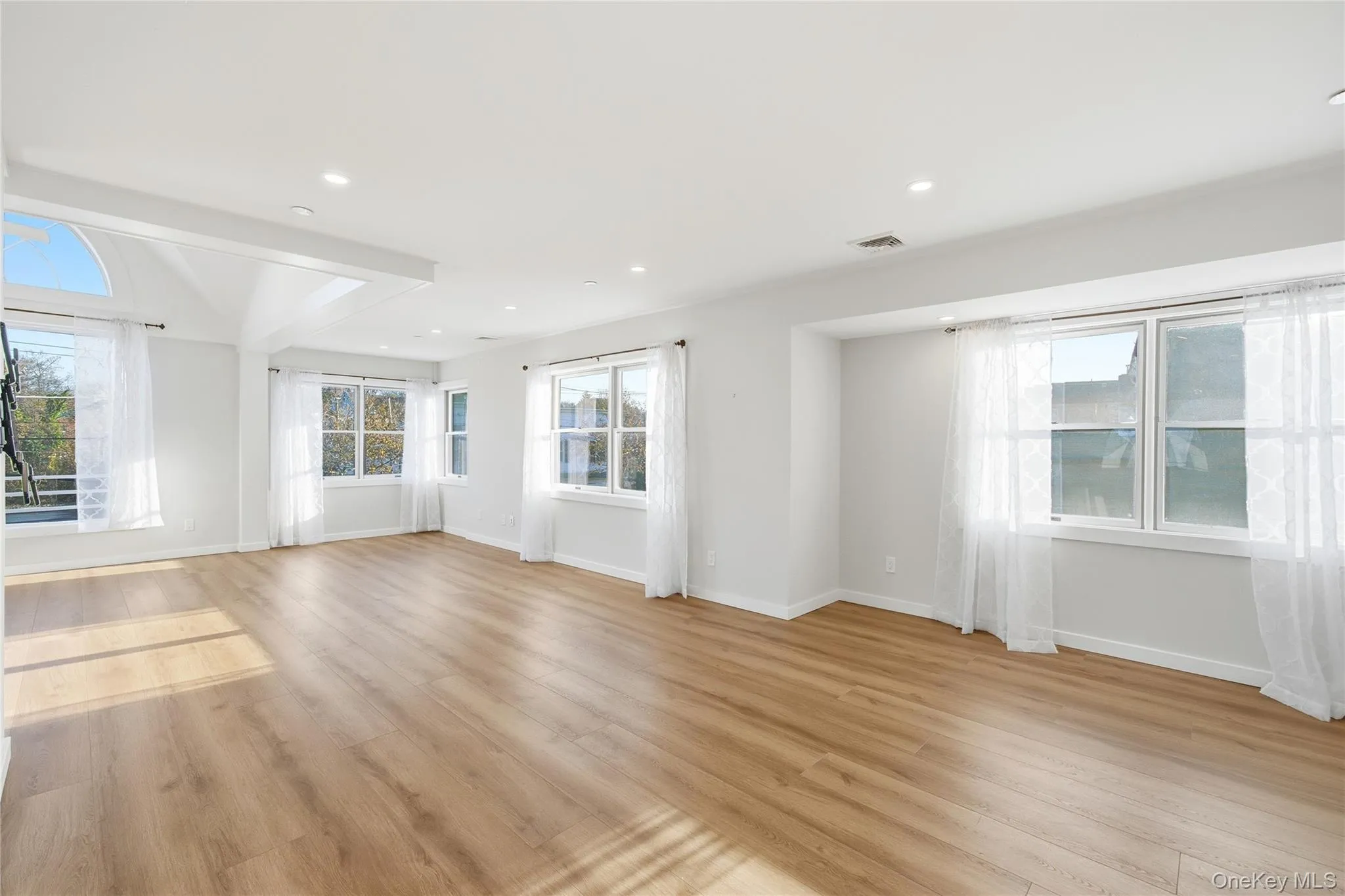 Living room featuring abundant natural light, light wood-type flooring, and recessed lighting Living room featuring abundant natural light, light wood-type flooring, and recessed lighting