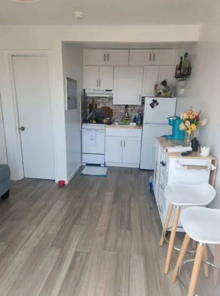 Kitchen with white appliances, dark wood-style floors, tasteful backsplash, under cabinet range hood, and light countertops Kitchen with white appliances, dark wood-style floors, tasteful backsplash, under cabinet range hood, and light countertops