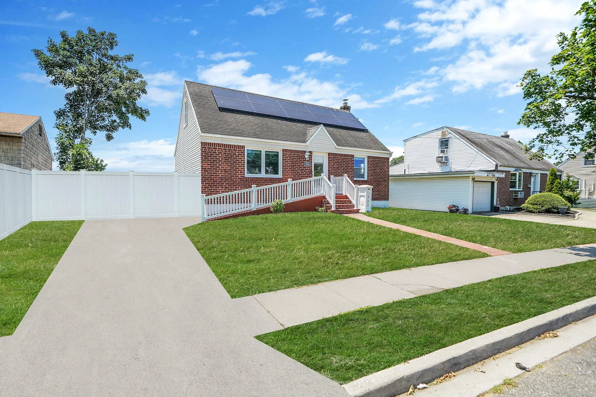 View of front of home featuring driveway, solar panels, brick siding, and a shingled roof View of front of home featuring driveway, solar panels, brick siding, and a shingled roof