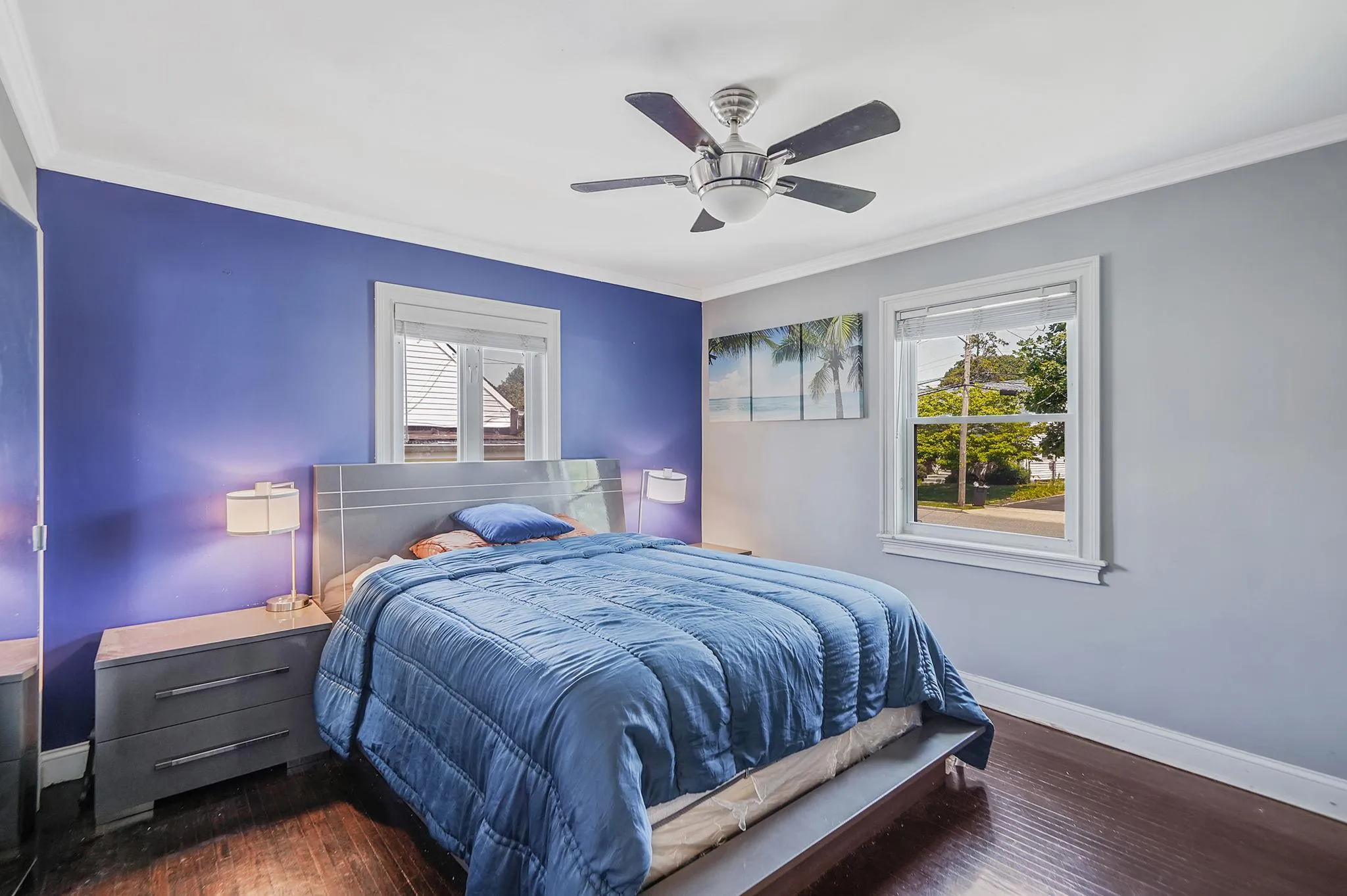 Bedroom with multiple windows, ornamental molding, wood-type flooring, and a ceiling fan Bedroom with multiple windows, ornamental molding, wood-type flooring, and a ceiling fan