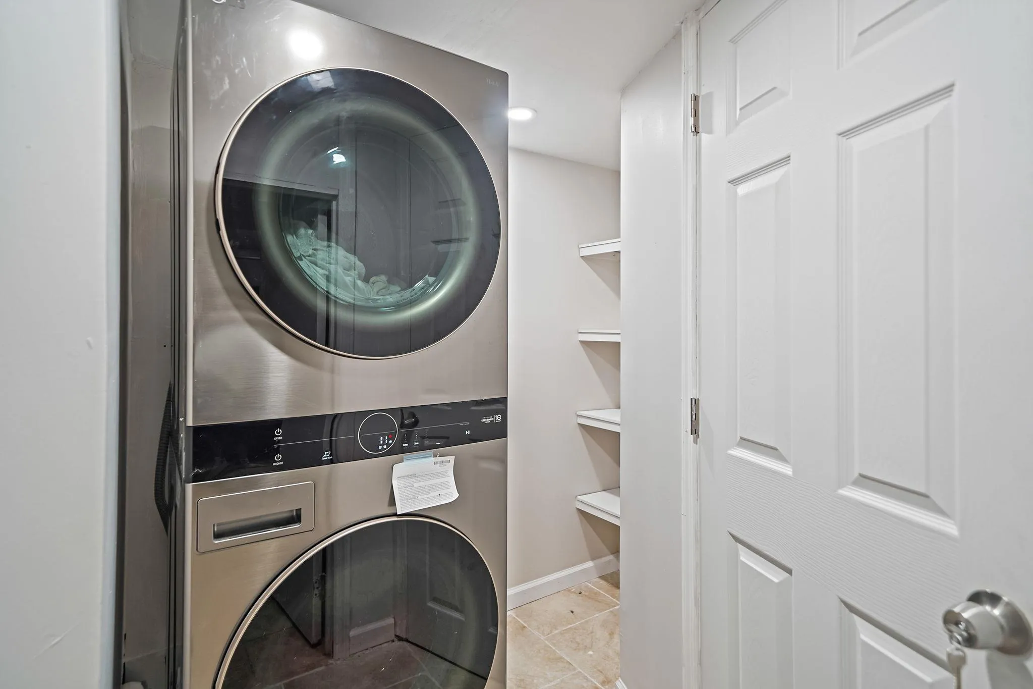 Laundry area featuring stacked washing machine and dryer and light tile patterned floors Laundry area featuring stacked washing machine and dryer and light tile patterned floors