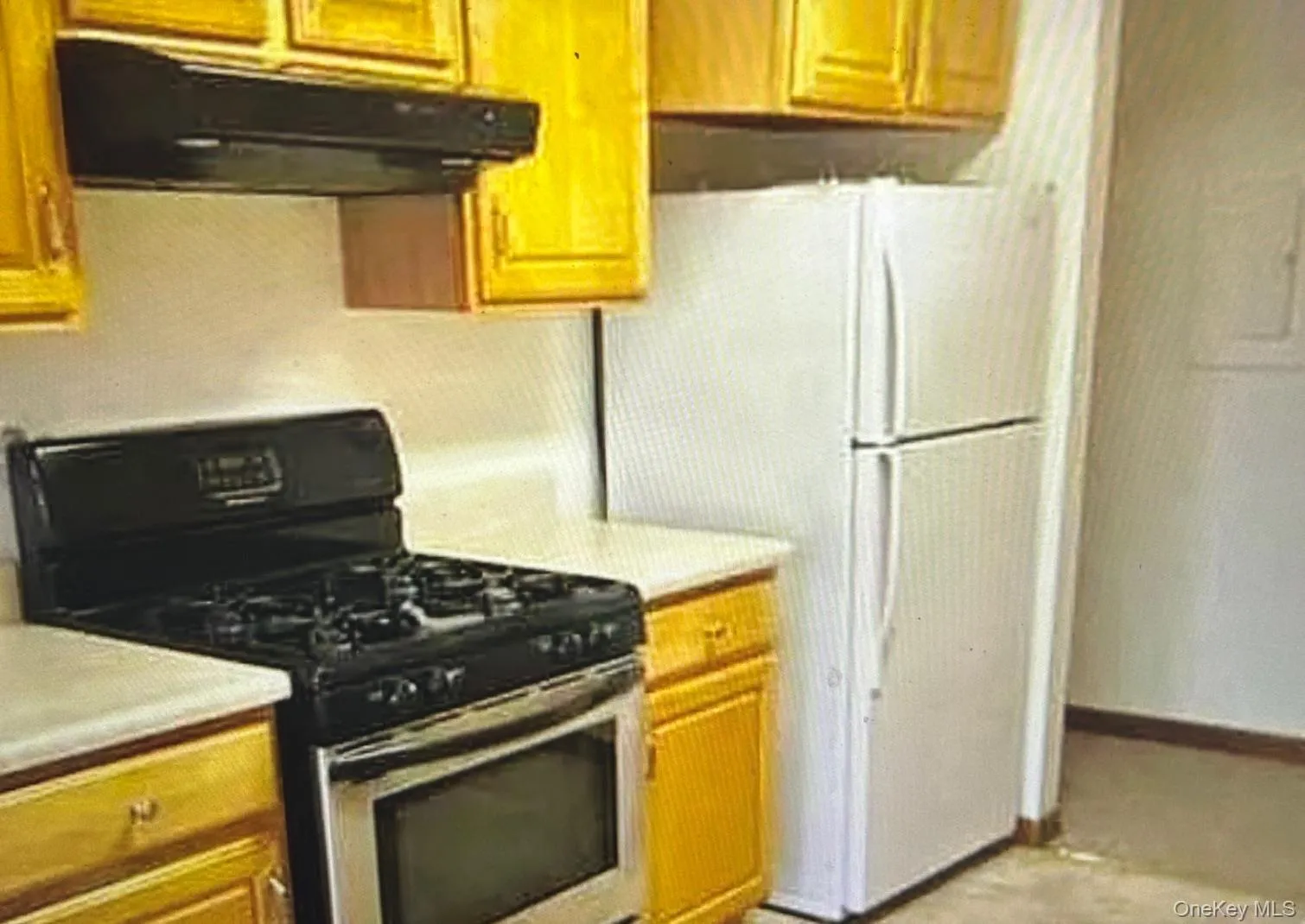 Kitchen featuring stainless steel range with gas cooktop, under cabinet range hood, light countertops, and brown cabinetry Kitchen featuring stainless steel range with gas cooktop, under cabinet range hood, light countertops, and brown cabinetry