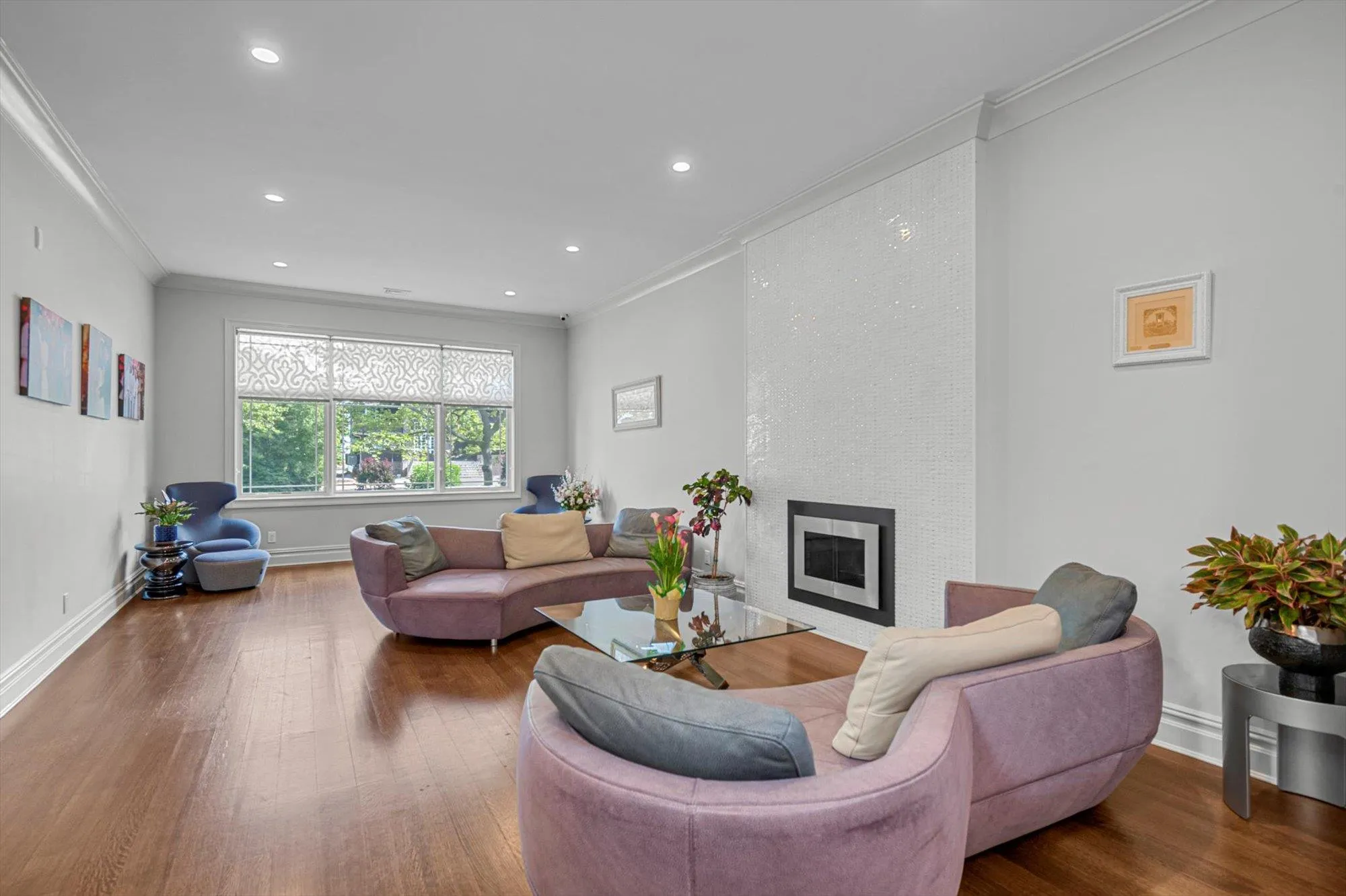 Living room with crown molding, wood finished floors, a large fireplace, and recessed lighting Living room with crown molding, wood finished floors, a large fireplace, and recessed lighting