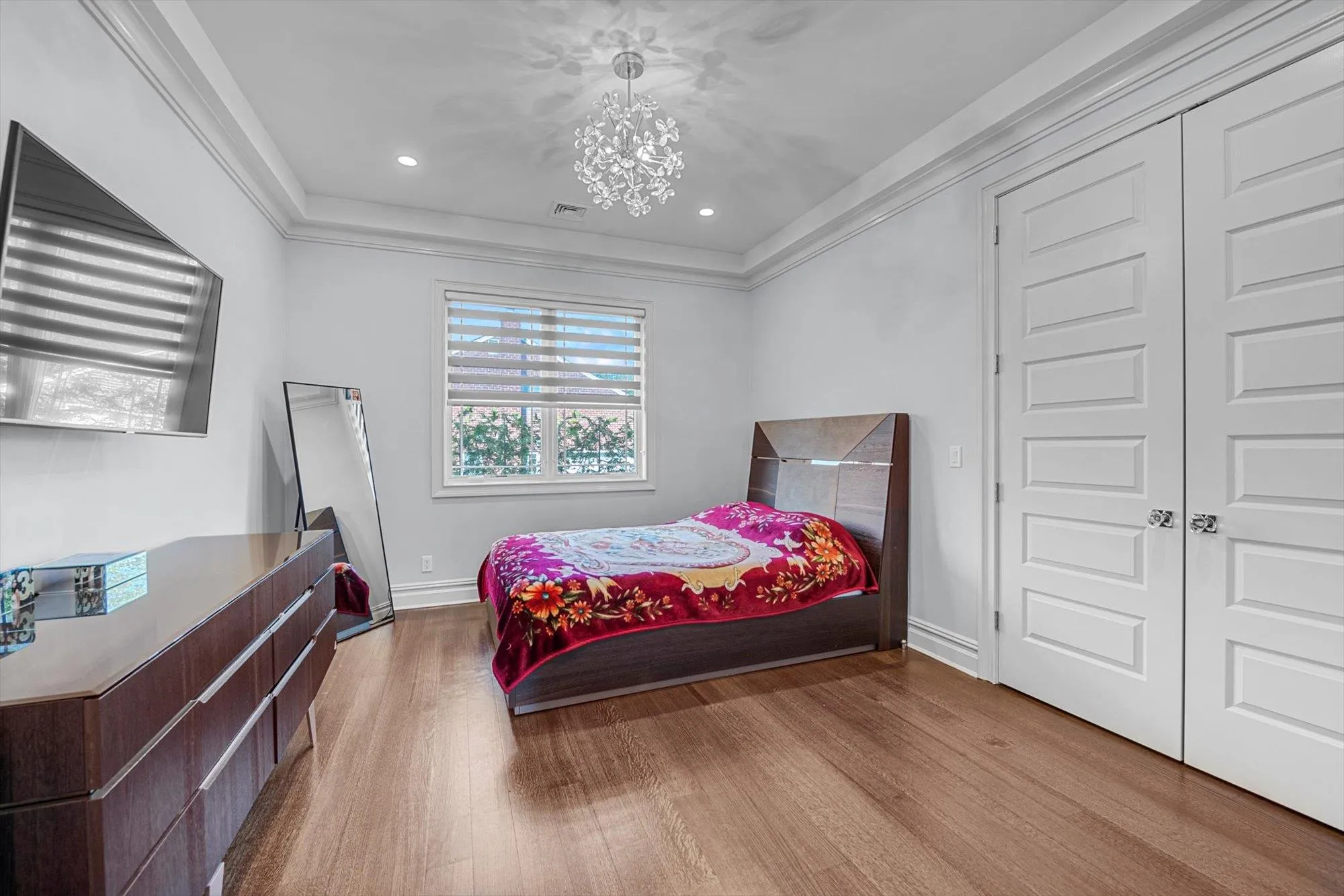 Bedroom featuring wood finished floors, a chandelier, ornamental molding, and a closet Bedroom featuring wood finished floors, a chandelier, ornamental molding, and a closet