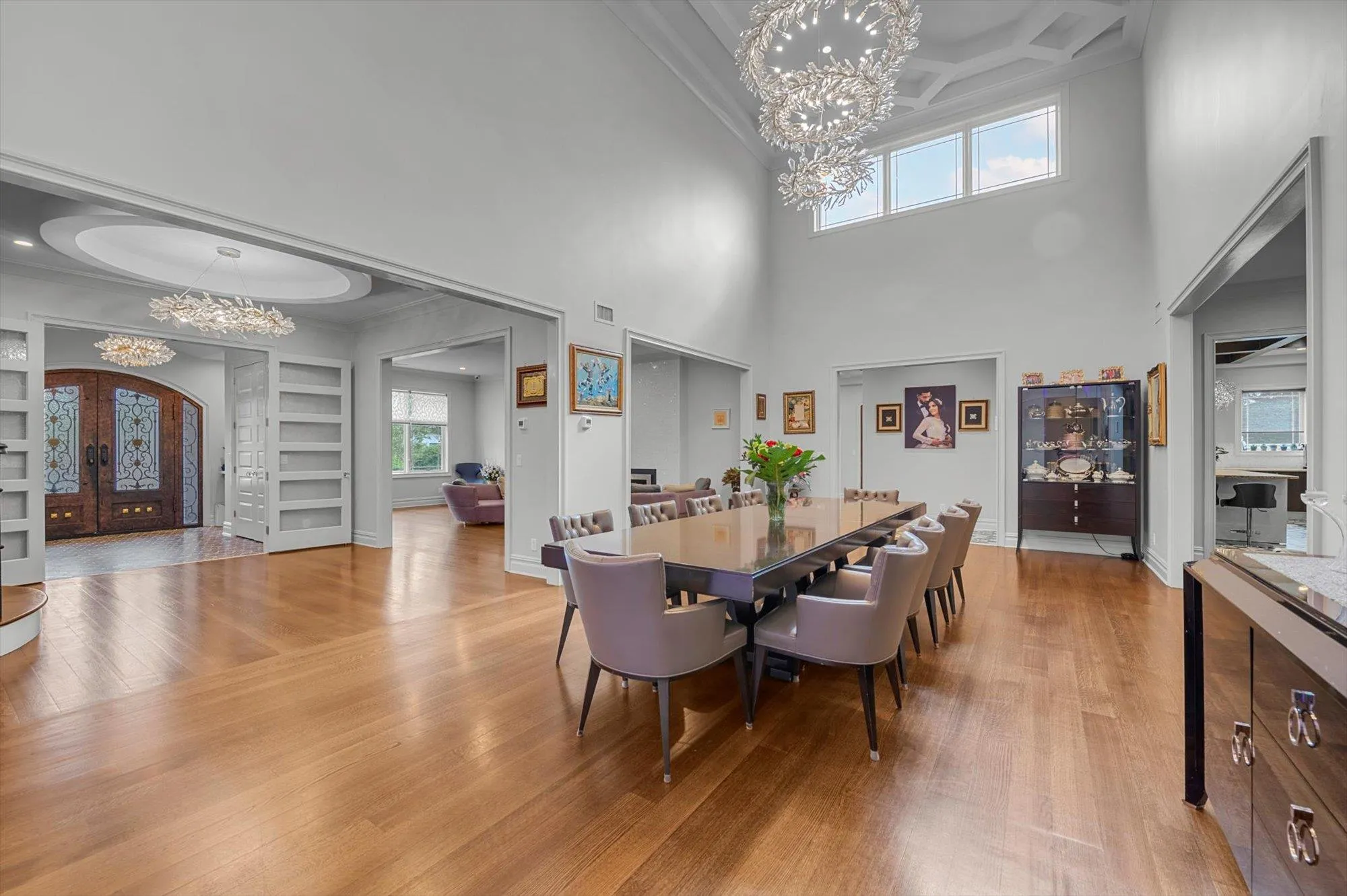 Formal Dining room with a chandelier, ornamental molding, light wood-style flooring, coffered ceiling, and a towering 20' ceiling Formal Dining room with a chandelier, ornamental molding, light wood-style flooring, coffered ceiling, and a towering 20' ceiling