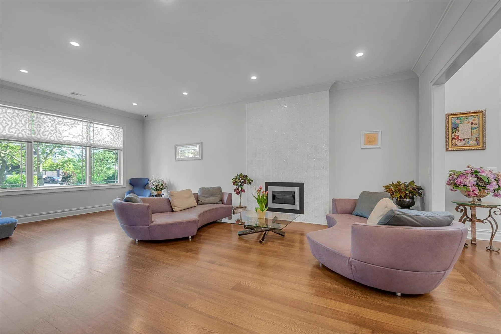 Living room with ornamental molding, light wood finished floors, recessed lighting, and a large gas fireplace Living room with ornamental molding, light wood finished floors, recessed lighting, and a large gas fireplace